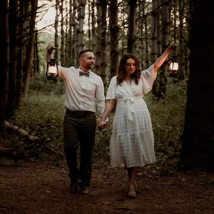 Elopement couple walking through Burr Oak Woods Conservation Area with lamps