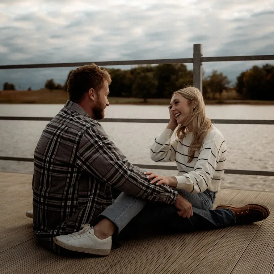 Couple sitting on a dock in cinematic fall lake session